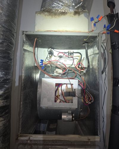 home therapist cooling heating and plumbing servicing a furnace with visible wiring and components for maintenance or repair