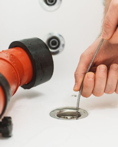 Drain Cleaning Tool Used In Bathtub With Orange Pipe And Water Tampa Fl