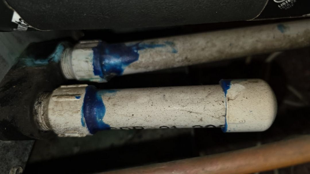 pipe repair work with blue sealant applied to joining sections of white plumbing pipes showing some dirt and wear