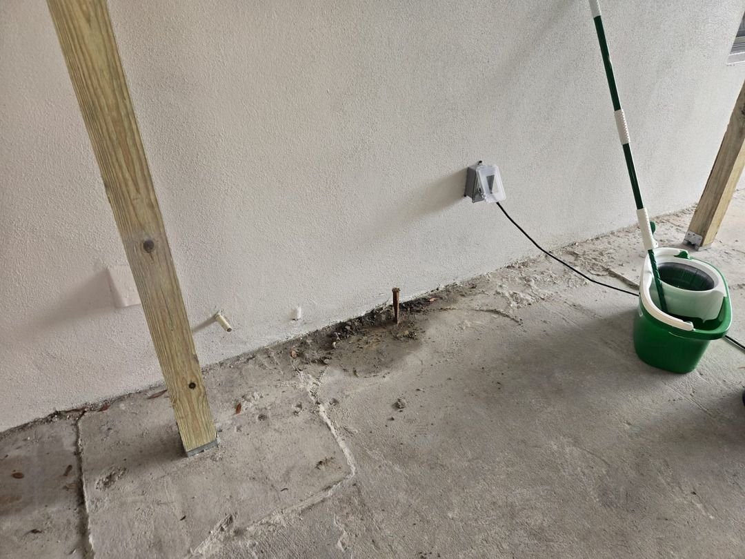 exposed concrete slab with a furring strip and a bucket suggestive of plumbing or electrical work being prepared