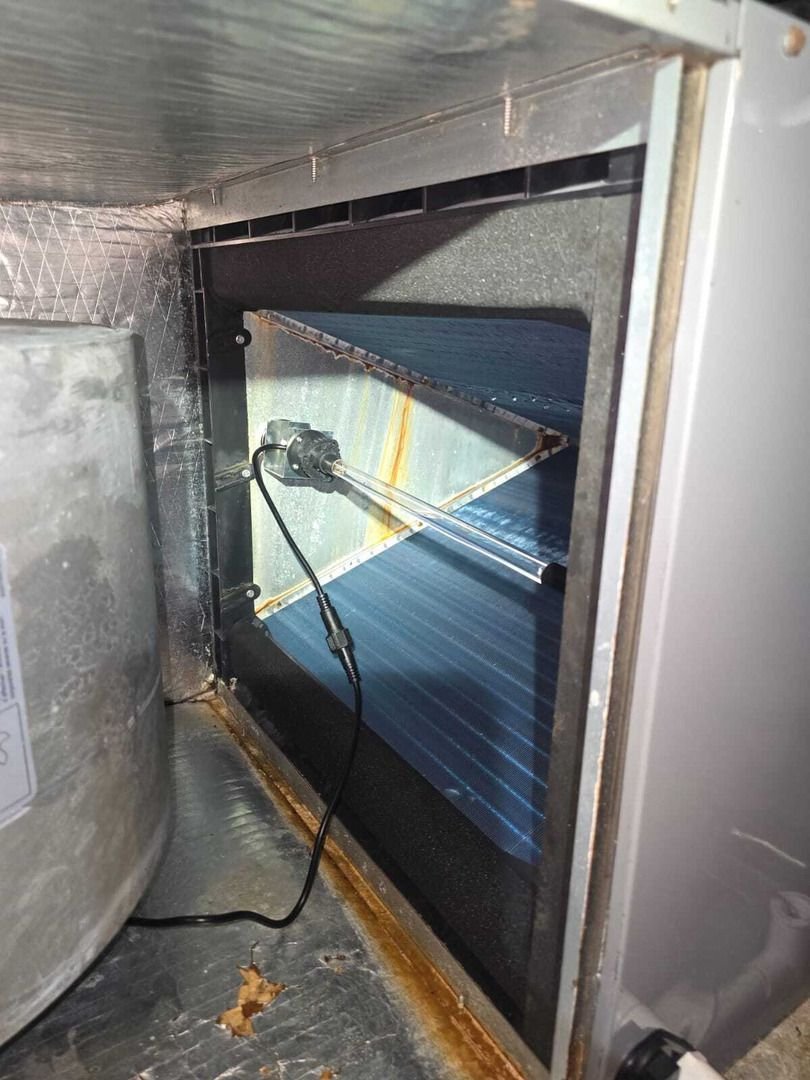 cleaning or inspecting a cooling unit with visible cooling fins and a wire connected to a component inside the unit