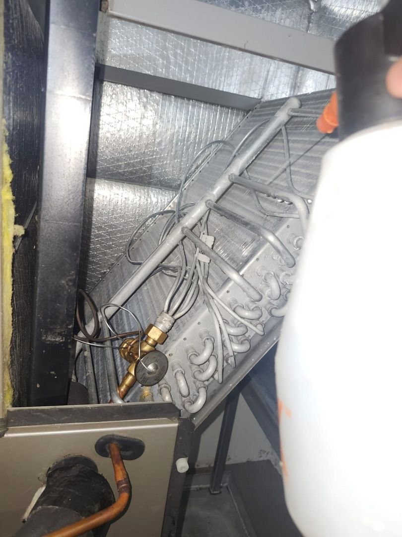 Cleaning And Maintaining An Air Conditioning Unit With Visible Components Like Coils And Piping In A Service Area