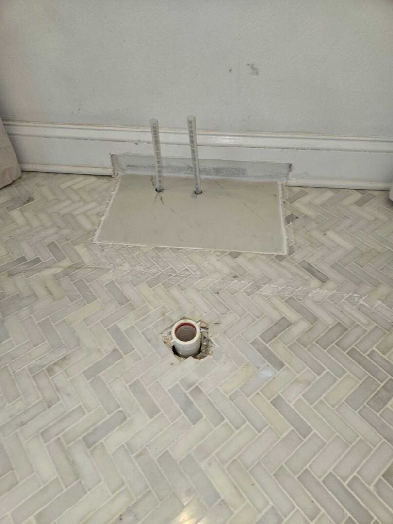 pipe installation or repair in a tiled floor with visible fittings and opening for plumbing connections
