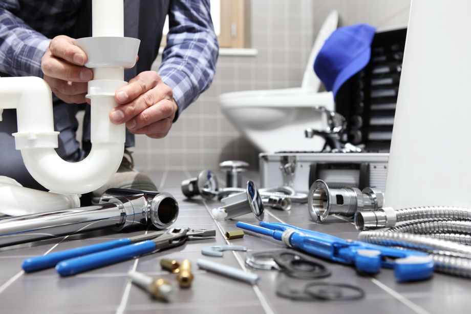 Plumber And Electrician Working In Bathroom With Tools