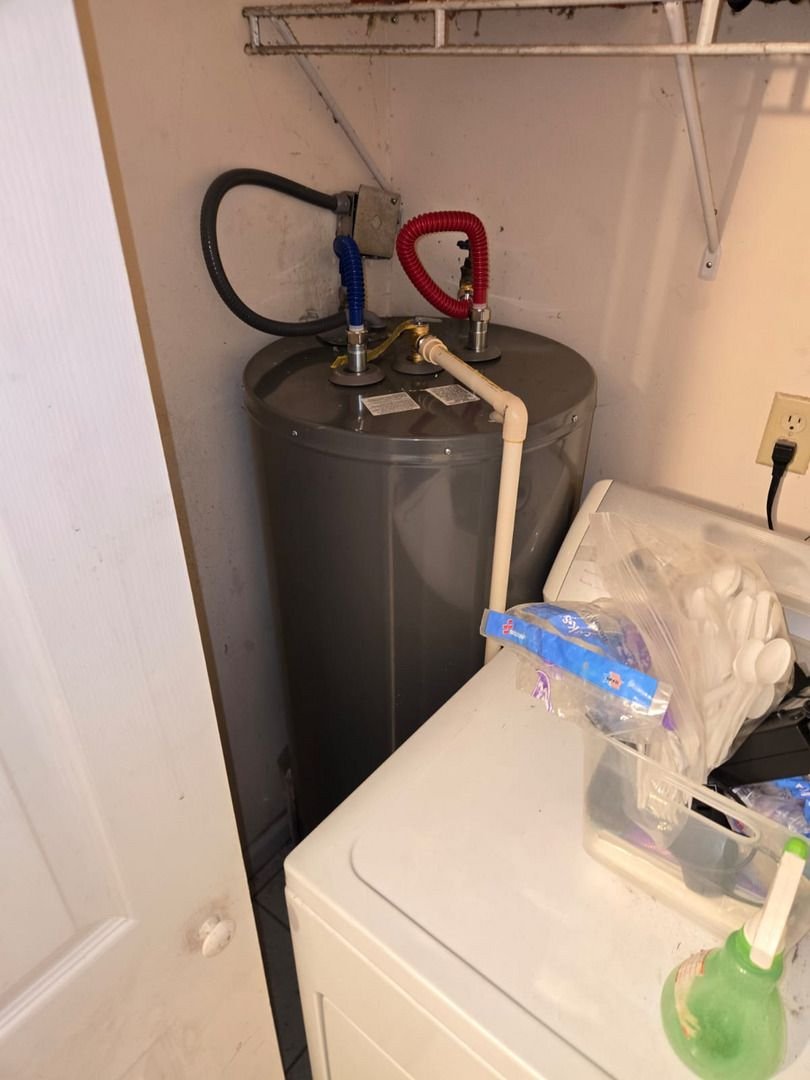 water heater installation visible with hot and cold water connections on top and nearby laundry equipment