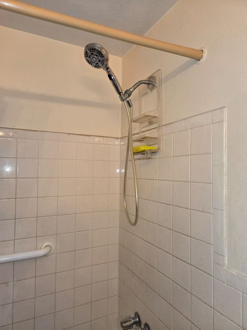 shower head installation with a handheld shower attachment in a bathroom setting on tiled walls