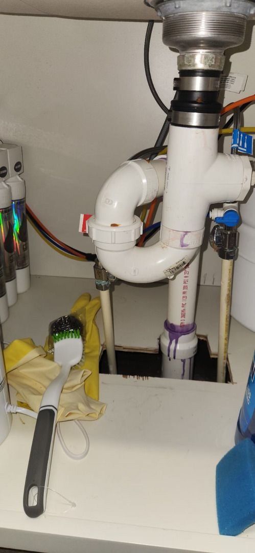 plumbing maintenance with cleaning tools and gloves near pipes and plumbing connections under a sink