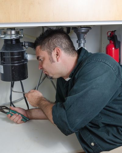 Electrician Fixing Sink Disposal In Kitchen Cabinet Using Tools Tampa Fl