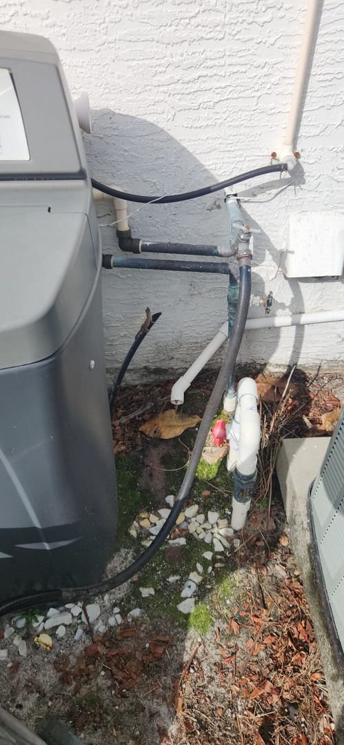 pipes and hoses connected to a unit against a wall likely related to heating or cooling system maintenance