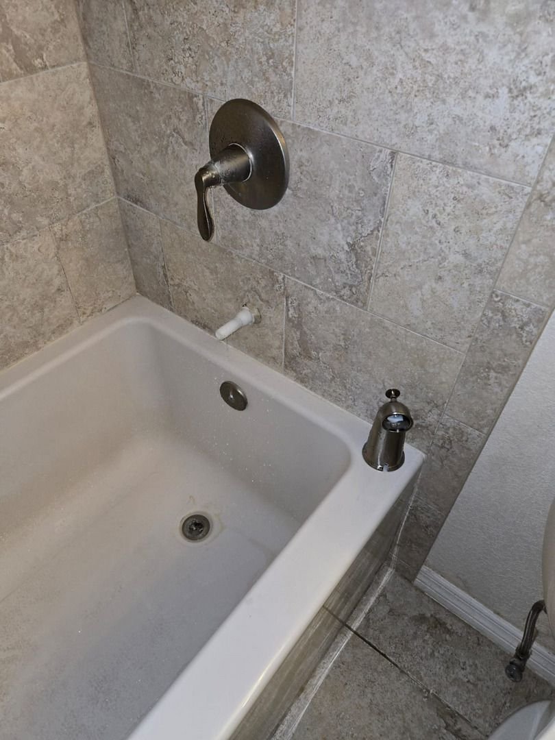 bathroom plumbing installation of a tub faucet in a tiled shower area with visible plumbing details