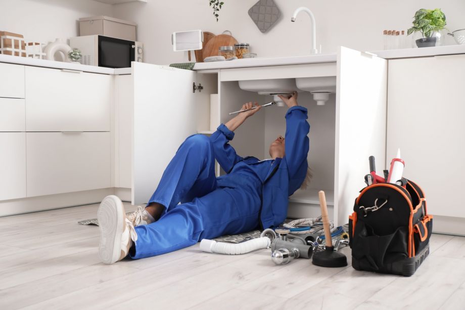 Woman Fixing Sink In Kitchen With Tools And Equipment