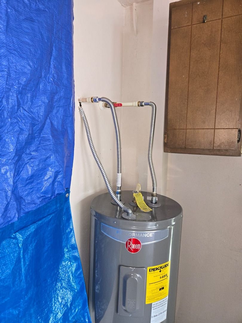 plumbing service installing or repairing a water heater with flexible hoses and a blue tarp for protection