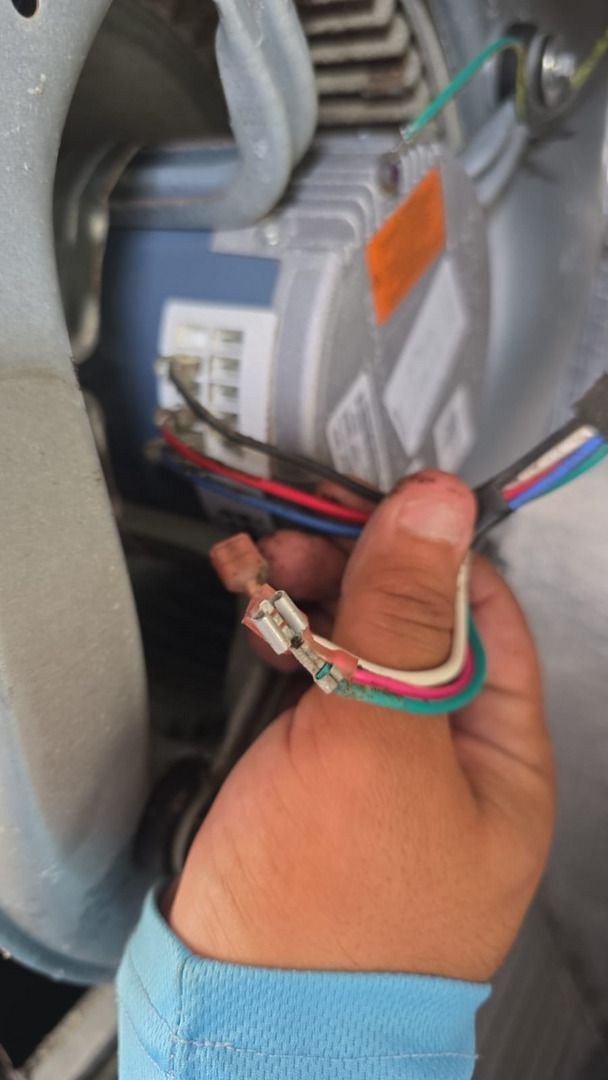 technician repairing or replacing electrical connections in a heating or cooling unit using various colored wires