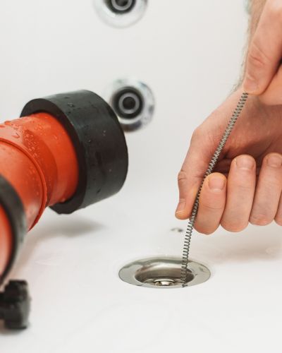 Drain Cleaning Tool Used In Bathtub With Orange Pipe And Water Tampa Fl