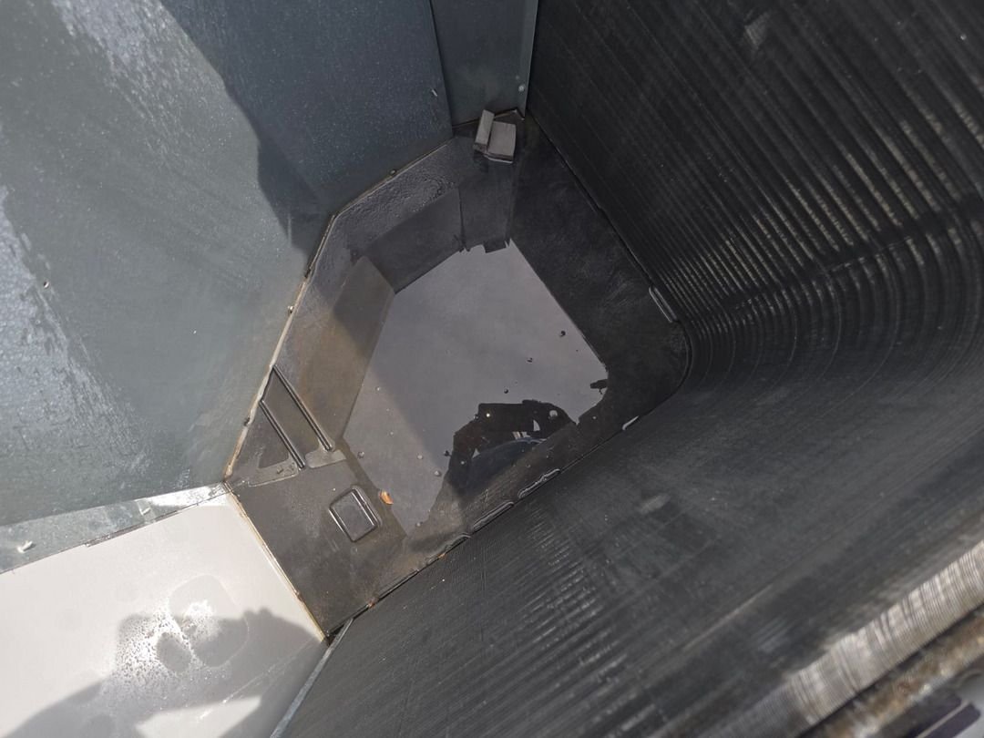 water pooling in a dark container with smooth surfaces possibly related to plumbing or cooling system maintenance