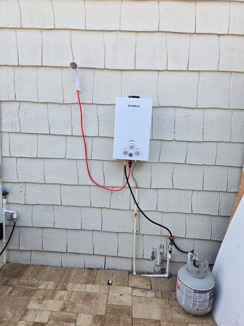 installing a tankless water heater on an exterior wall with connected gas and water lines and a propane tank nearby