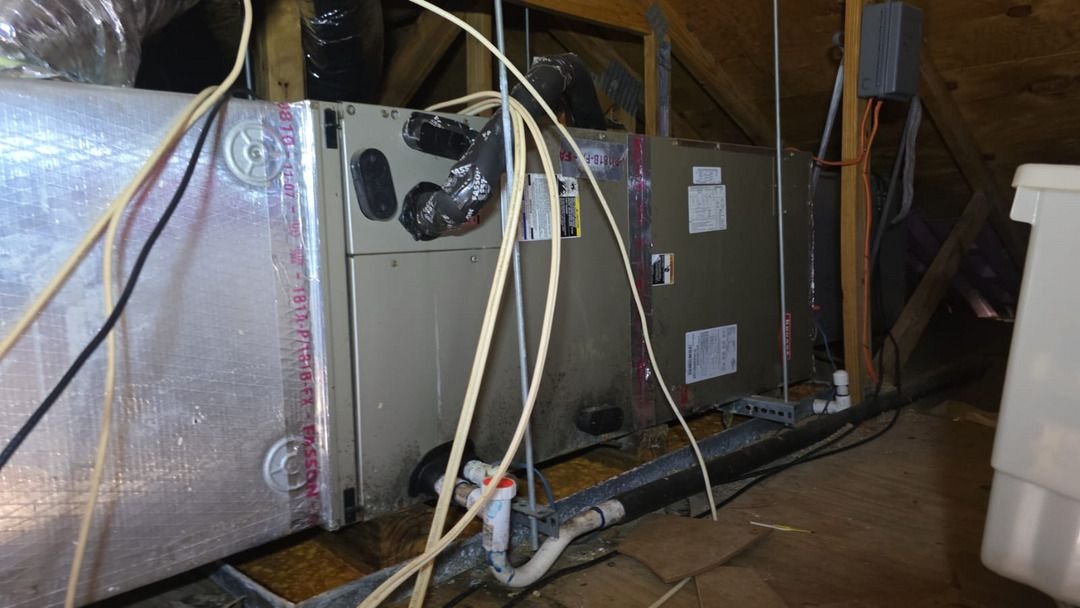 servicing heating and cooling units with exposed ductwork and electrical connections inside an attic space