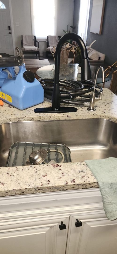 a black kitchen faucet with a portable blue appliance nearby showing plumbing work in a modern kitchen setting