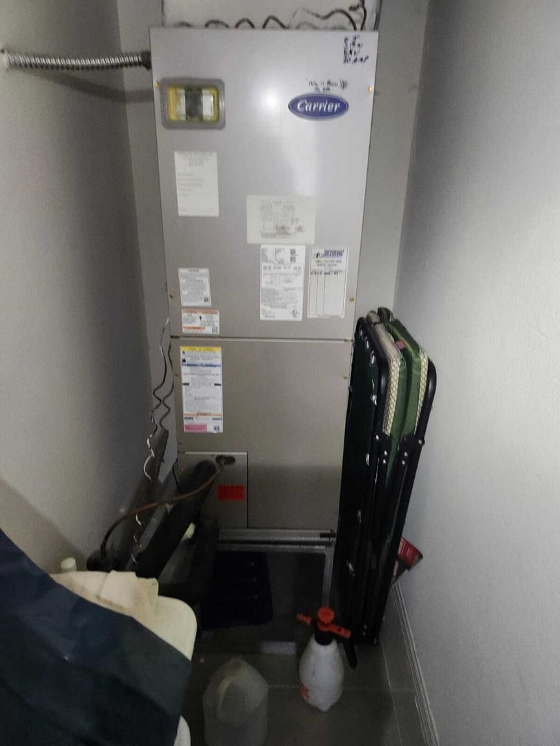 Furnace Installation In A Utility Closet With Tools And Supplies Nearby Including A Spray Bottle And Folding Chair