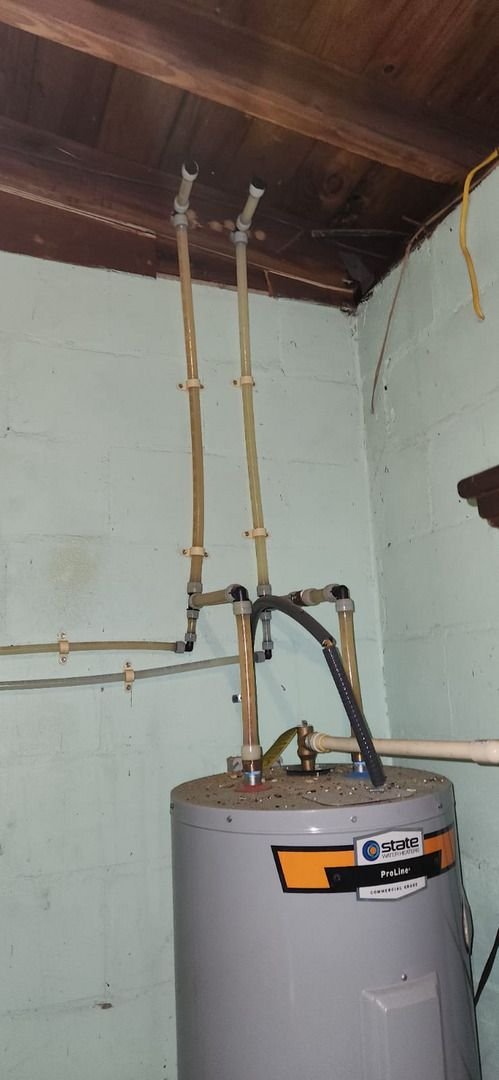 water heater installation with multiple pipes and fittings connected to a tank in a basement setting