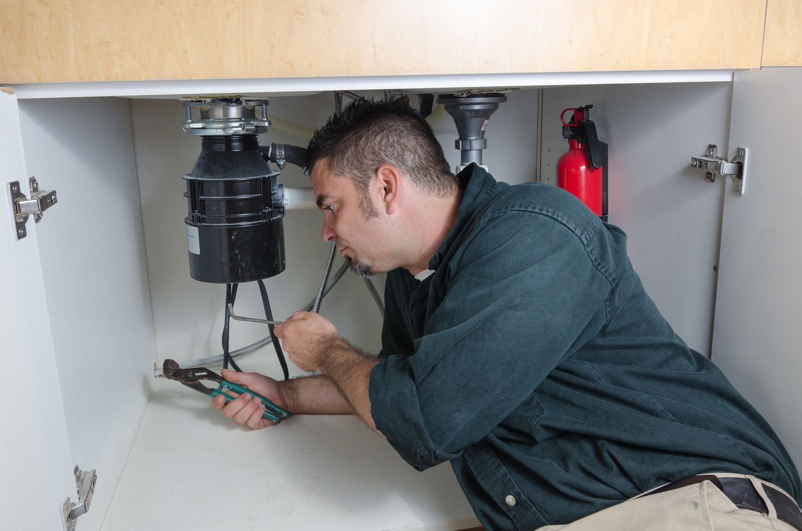 Electrician Fixing Sink Disposal In Kitchen Cabinet Using Tools