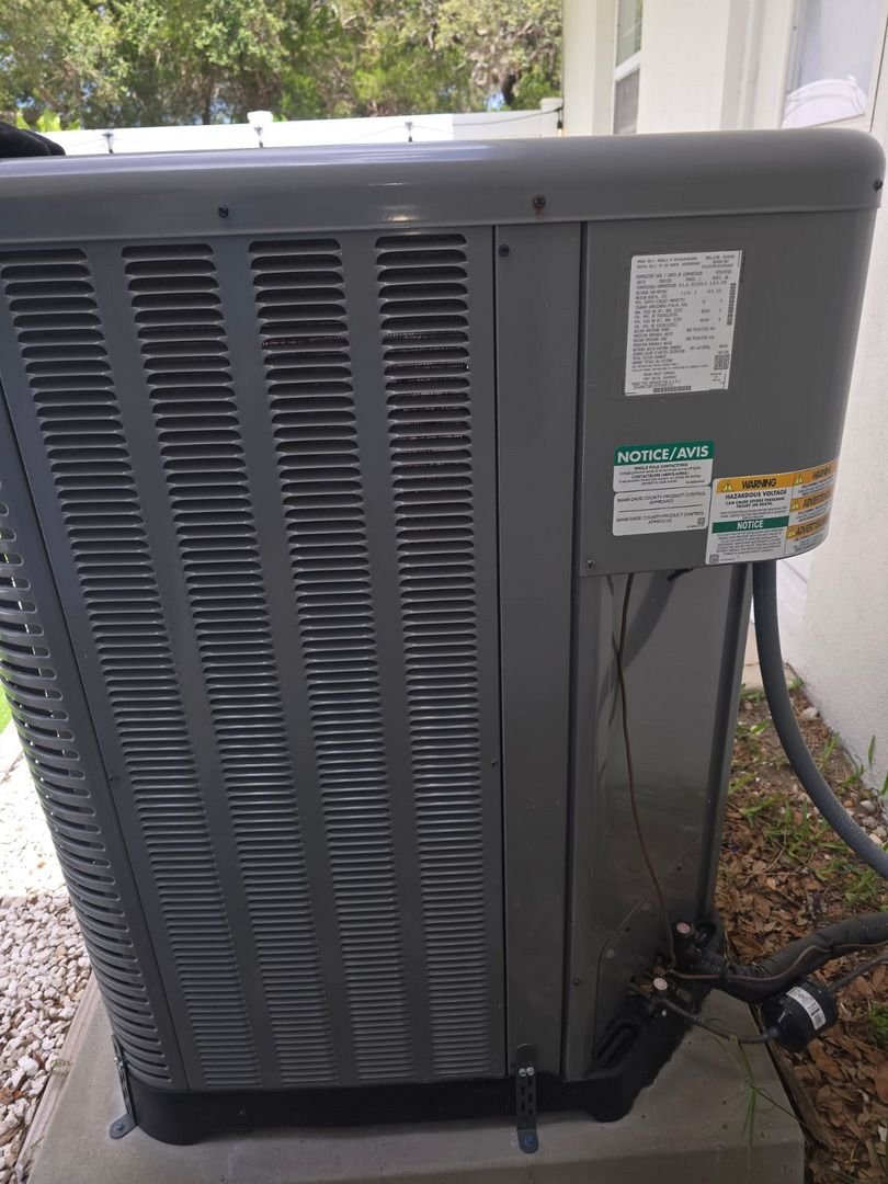 home therapist cooling heating and plumbing inspecting an outdoor air conditioning unit with visible components and labels