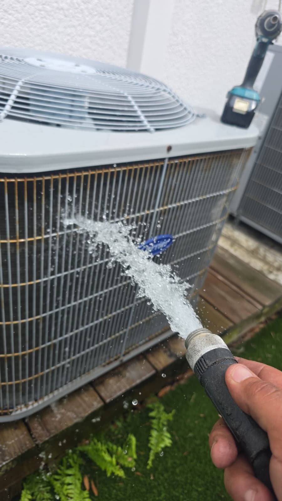 Home Therapist Visit #3: Cleaning outdoor AC unit in Tampa, FL 33619 with hose to remove debris.