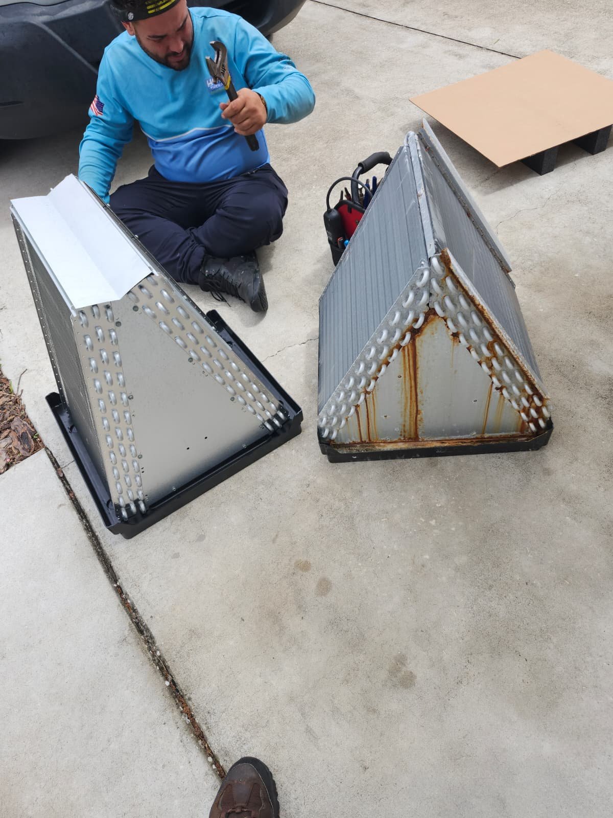 Technician comparing old and new air handler coils in Tampa, FL 33624.