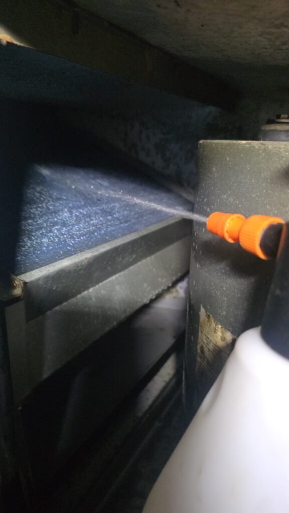 Technician spraying coil cleaner on an indoor AC coil during maintenance in Tampa, FL 33604