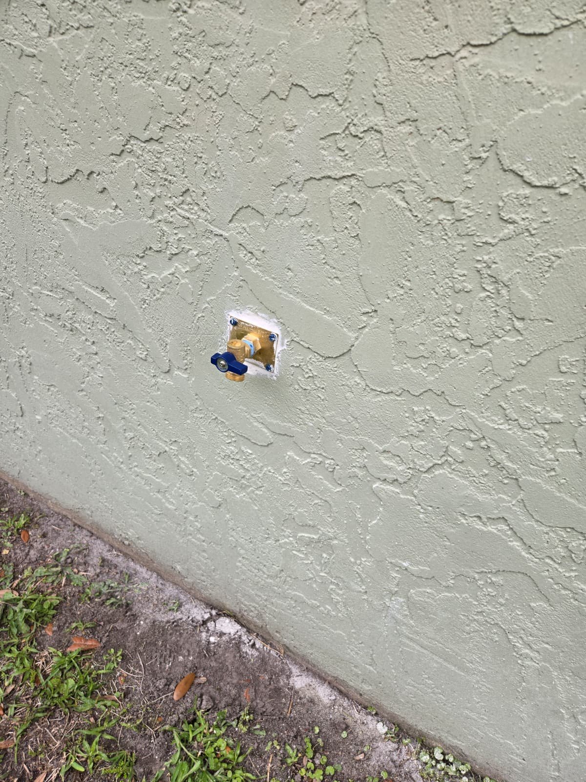 Outdoor water spigot on stucco wall for HVAC service in Tampa, FL 33624.