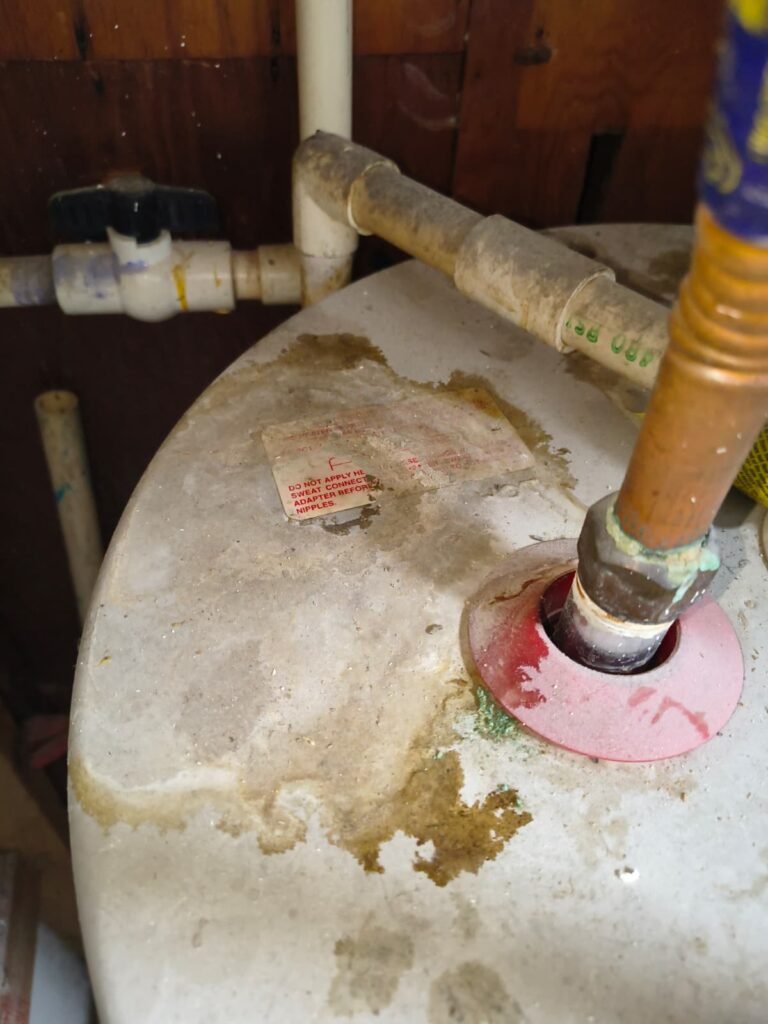 Rust stains on top of an old water heater and green corrosion on its copper line in Tampa, FL 33624.