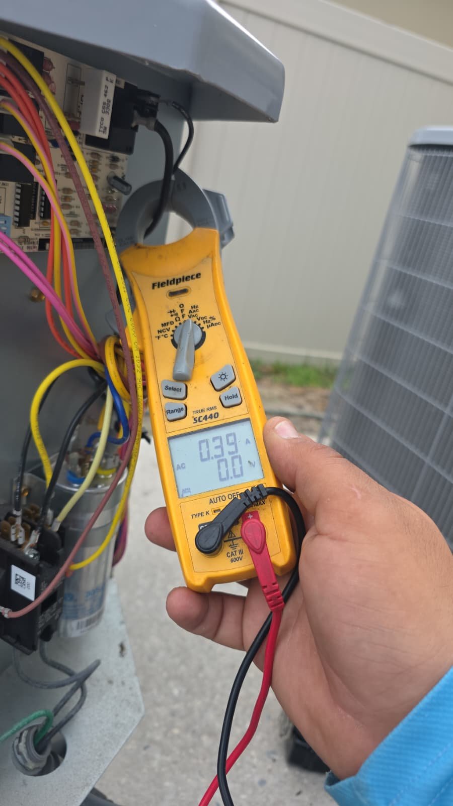 Technician using a multimeter on AC unit during Visit #3 in Plant City, FL 33566.