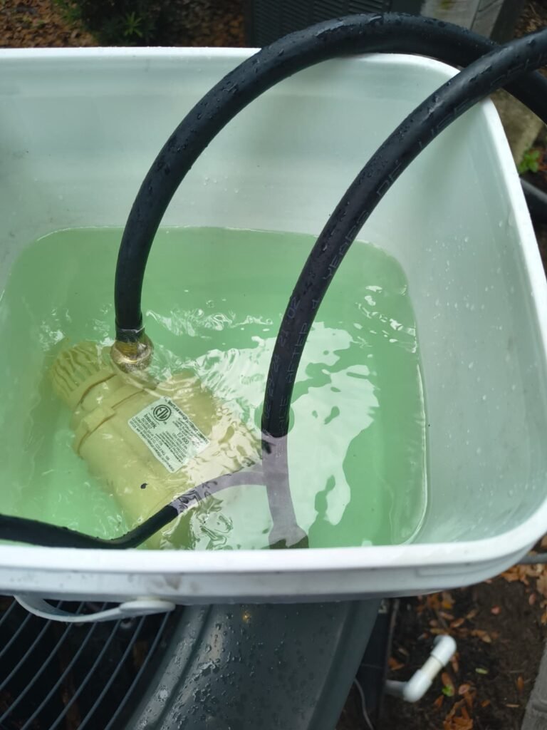 A pump and hoses in a bucket during a water heater flush in Lithia, FL 33547.