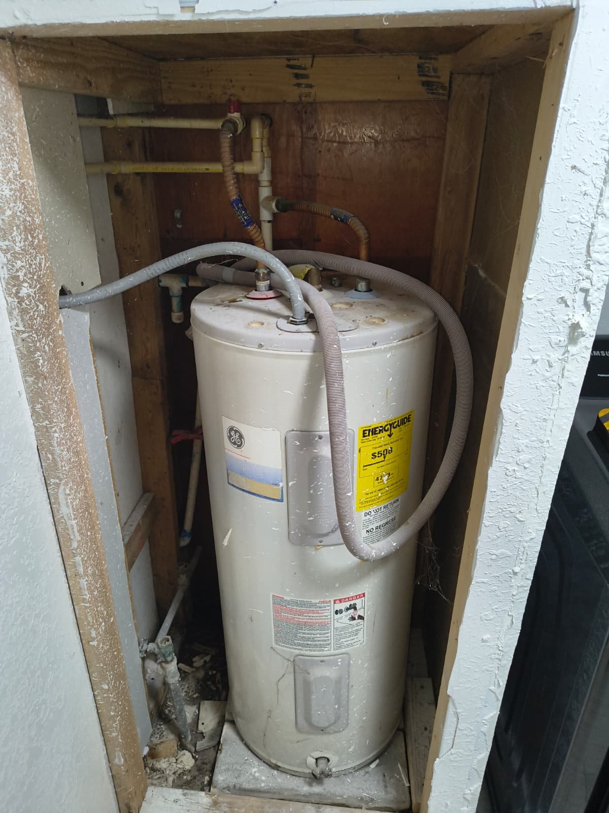 In-progress water heater installation in Tampa, FL 33624. Partially open wall space.