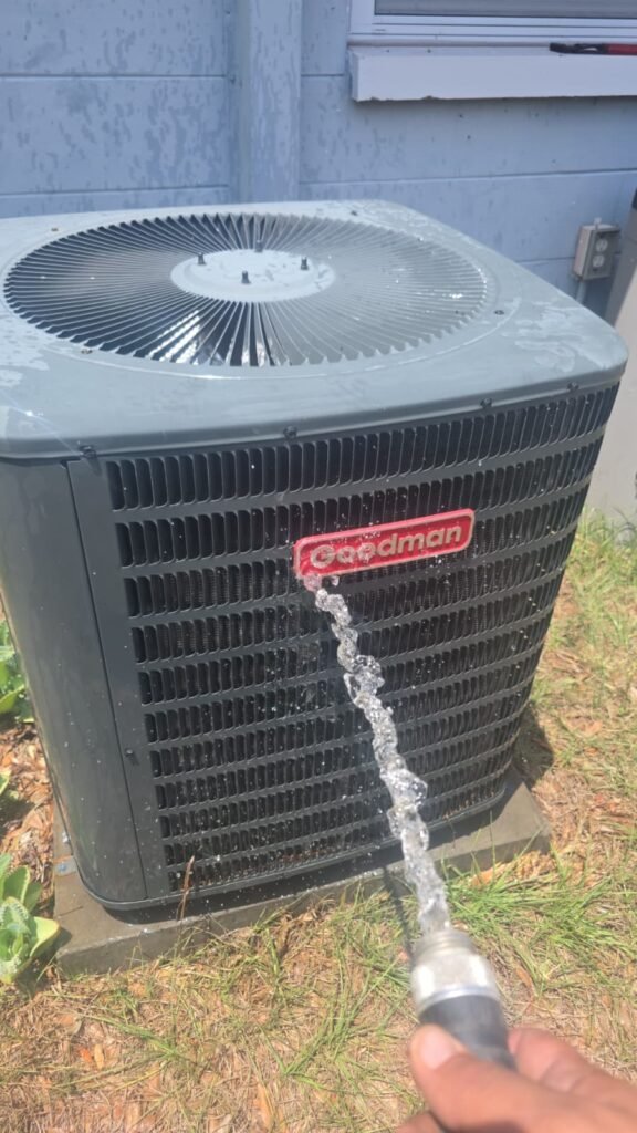 Rinsing a Goodman condenser coil during a tune-up in Tampa, FL 33624.