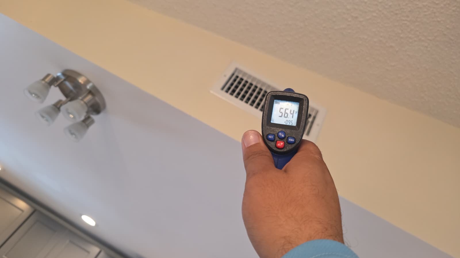 Temperature gun pointed at ceiling vent with lighting, part of AC service in St. Petersburg, FL 33703.