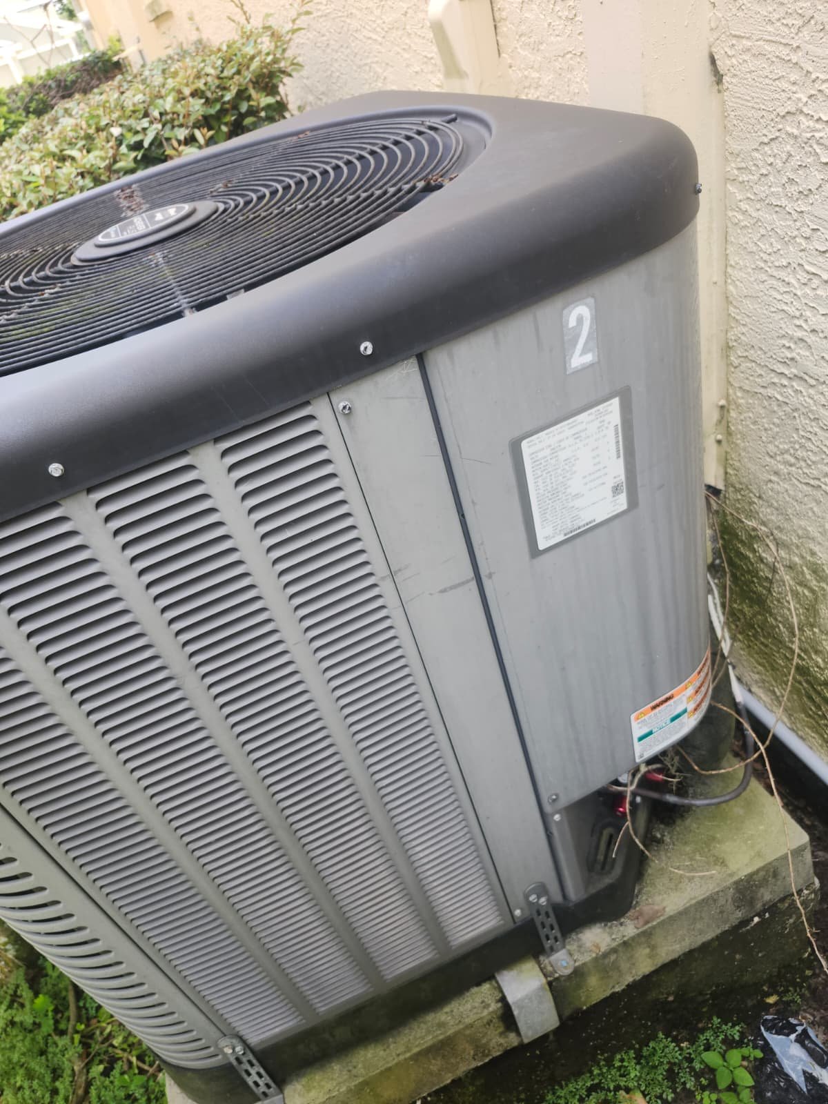 Outdoor AC unit beside house in Tampa, FL 33647 on concrete pad.