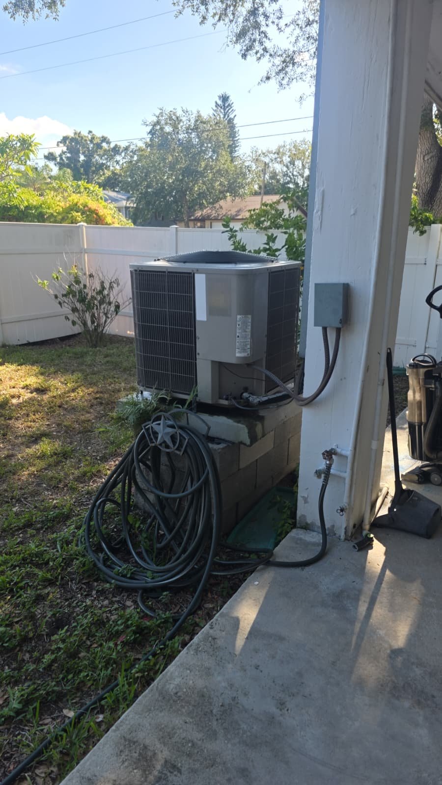 Outdoor AC unit on concrete base beside house in St. Petersburg, FL 33703.