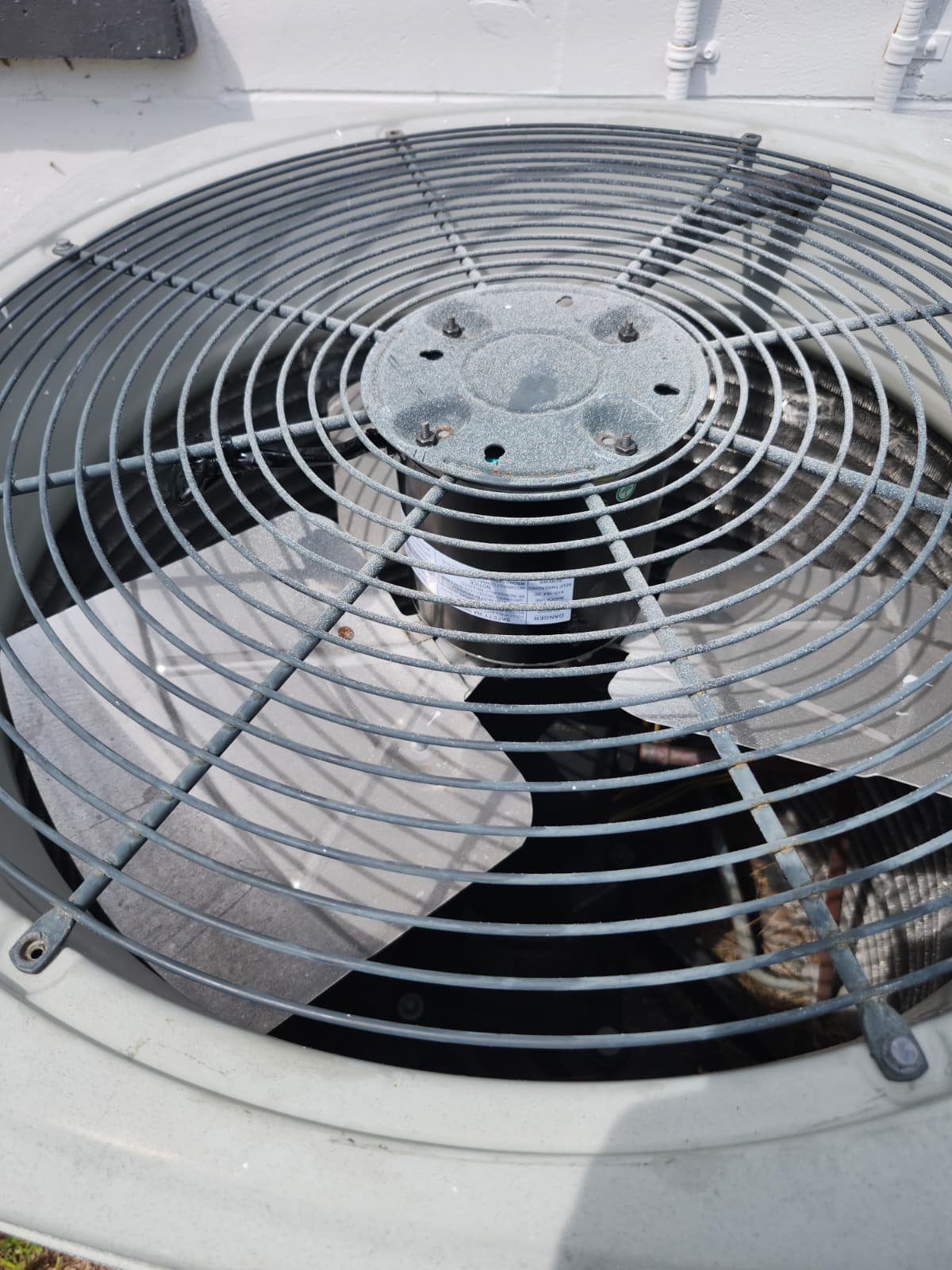 Close-up of a condenser fan motor with protective grill in St. Petersburg, FL 33712.