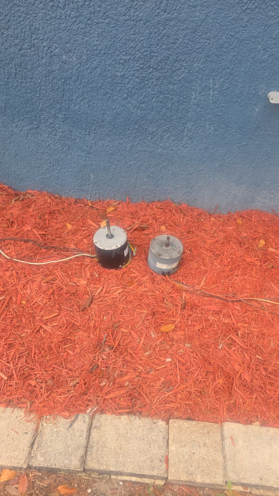 Condenser fan motors on mulch during repair in St. Petersburg, FL 33710.
