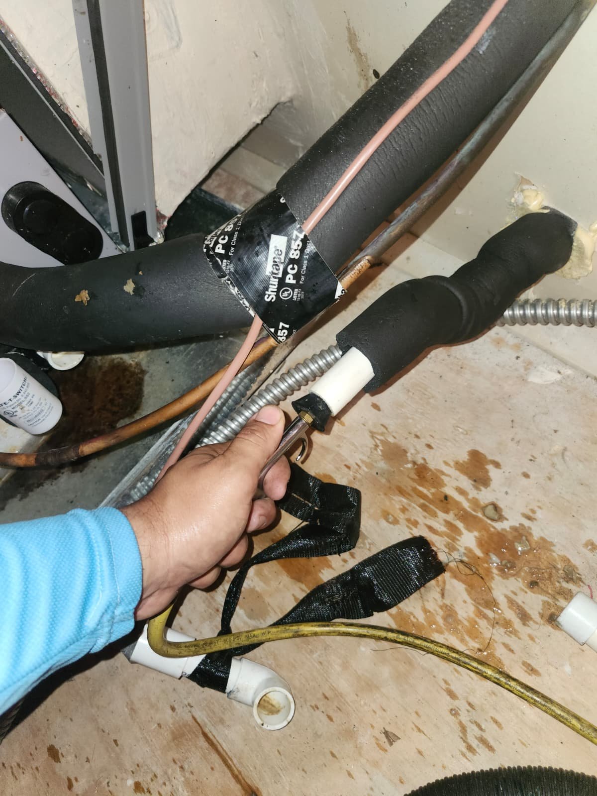 Person handling a drain line with visible piping and insulation, New Port Richey, FL 34655.