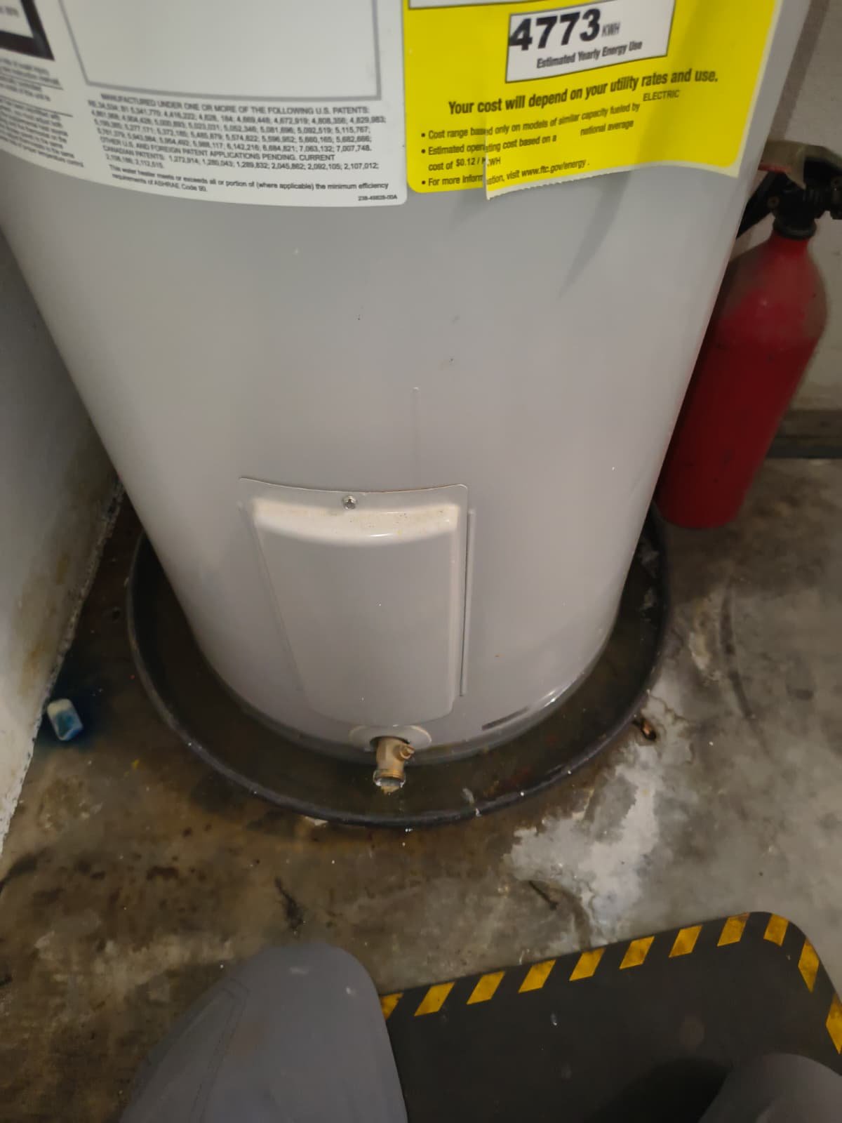Water heater in garage with drain valve, Riverview, FL 33579. Fire extinguisher nearby.