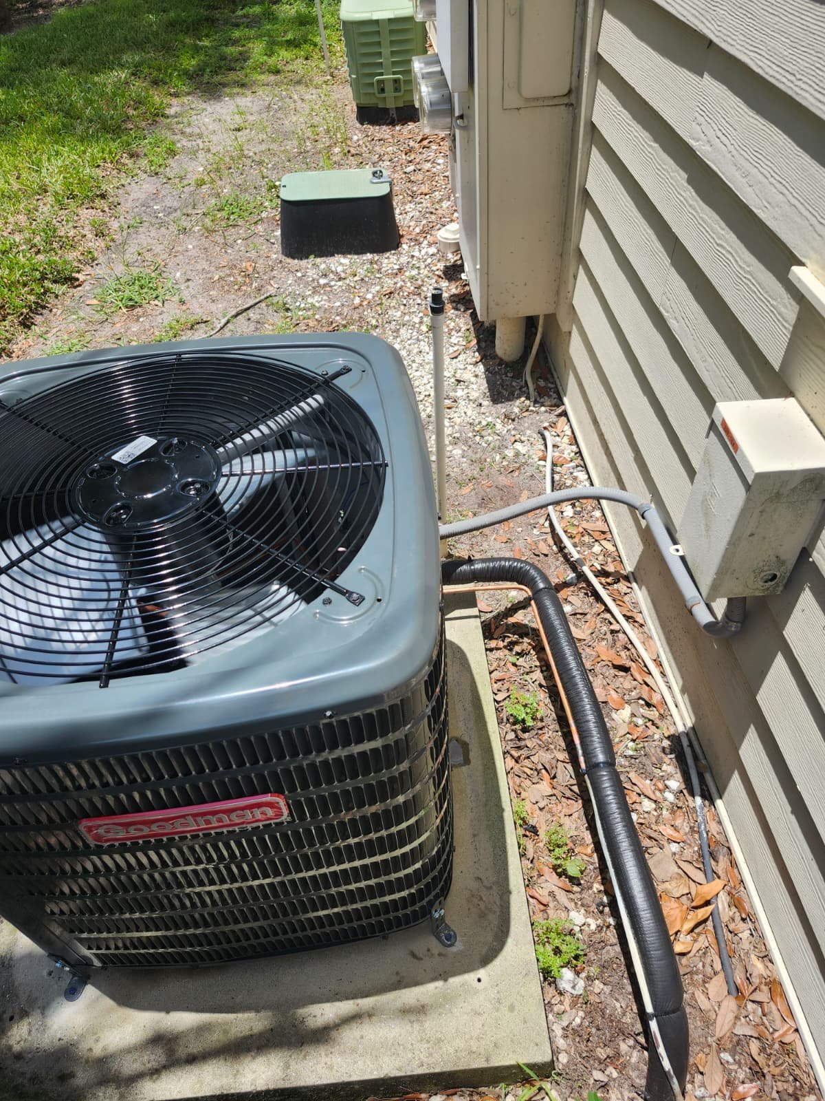 Side view of a Goodman AC unit with connected pipes in Brandon, FL 33511. Efficient piping.