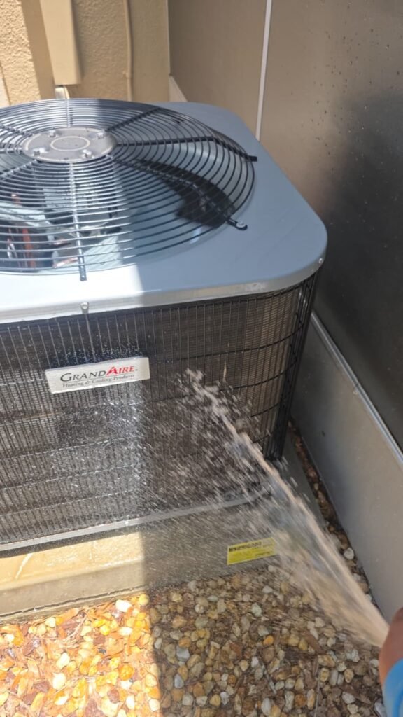 Rinsing the coil of a GrandAire condenser in Tampa, FL 33624.