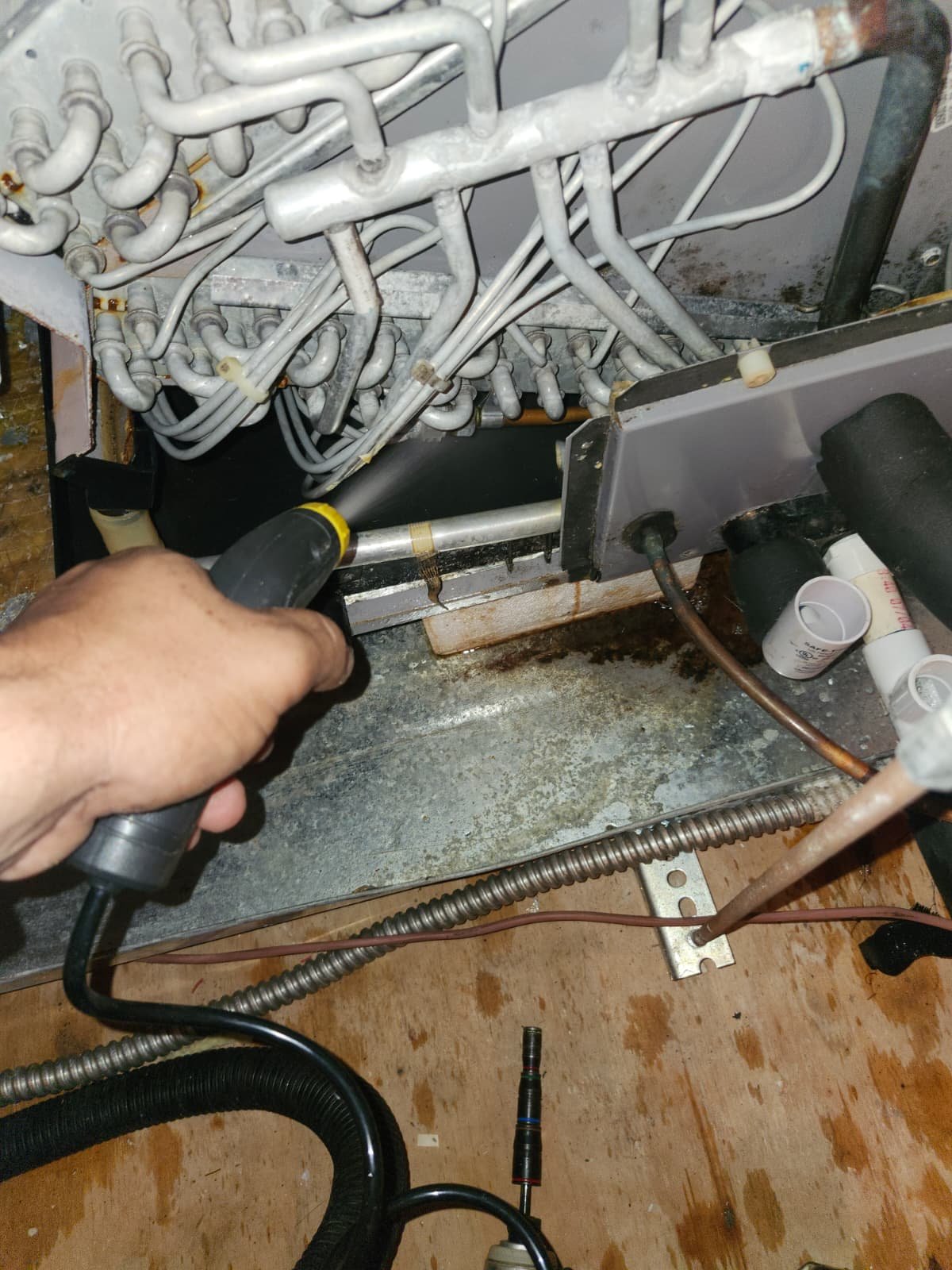 Person using a hose to flush a drain line in a mechanical room, New Port Richey, FL 34655.