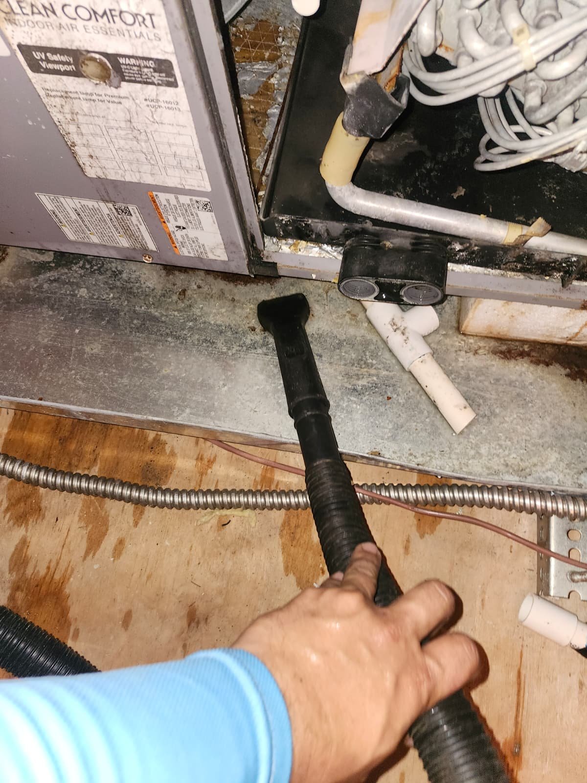 Person using a vacuum to clean around HVAC equipment, New Port Richey, FL 34655.