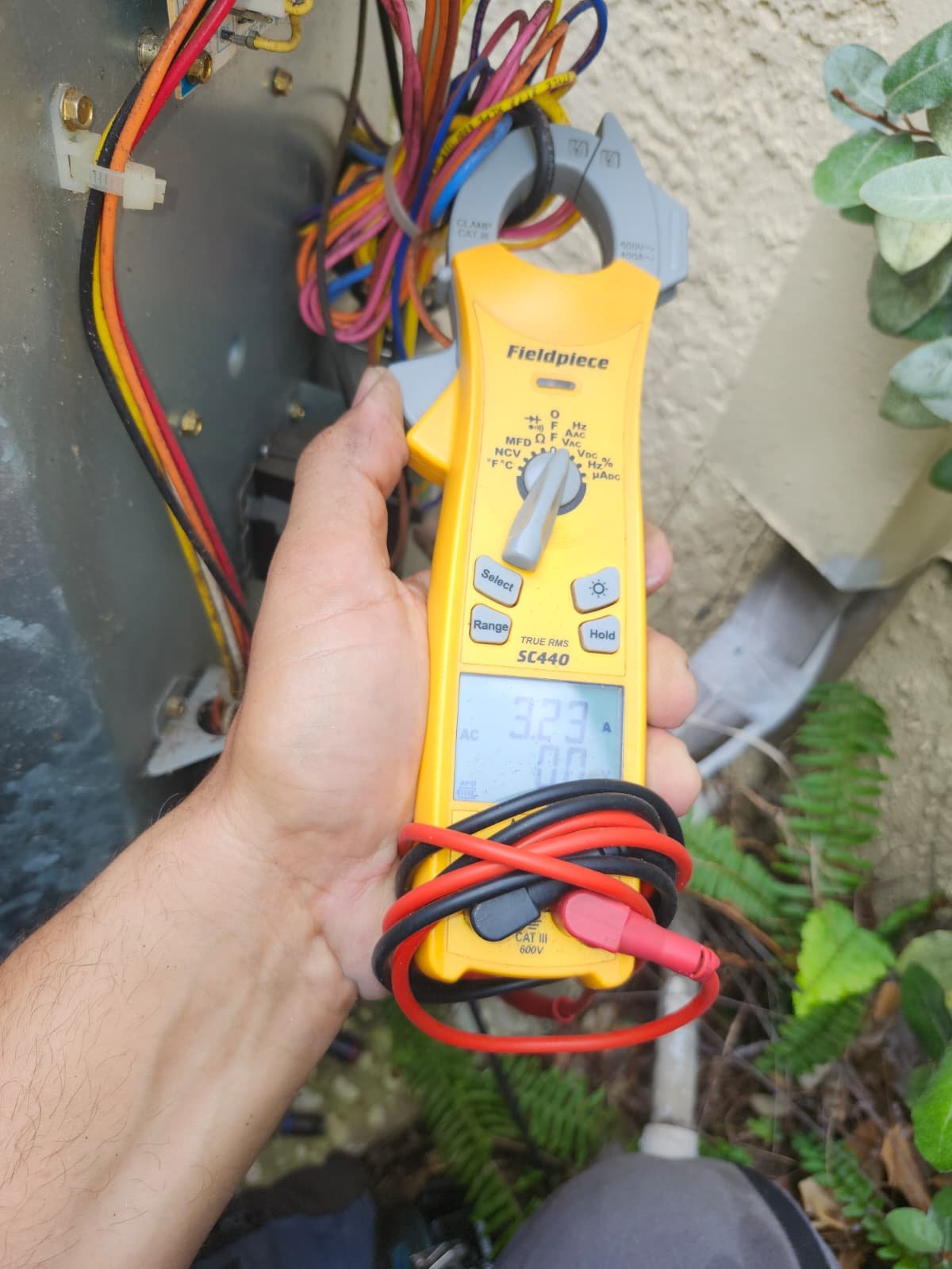 Technician checks HVAC unit with multimeter, Tampa, FL 33647.