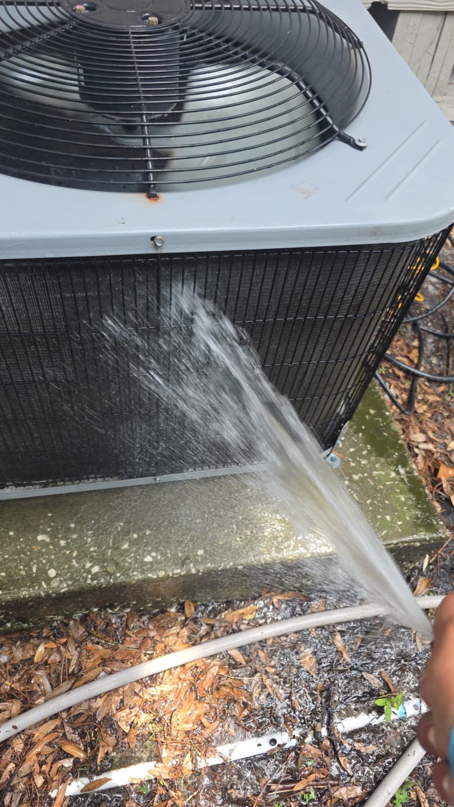 Outdoor AC Cleaning - Lutz, FL 33558 Cleaning outdoor AC condenser unit with hose in Lutz, FL 33558.