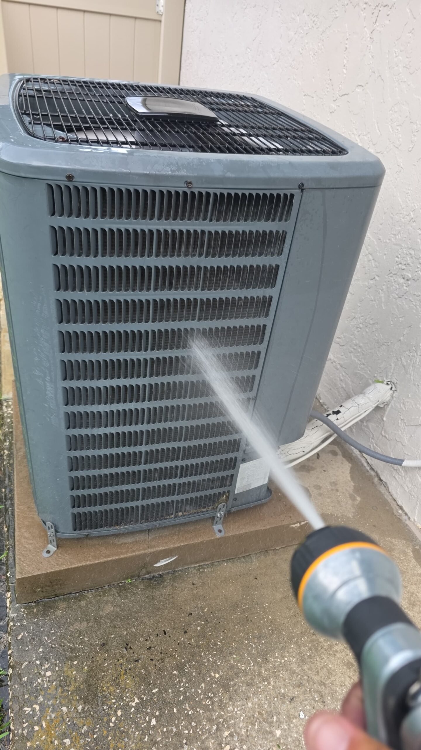 Cleaning process of outdoor AC unit with hose in Palm Harbor, FL 34684 during Premium Therapy Plan 2.0.