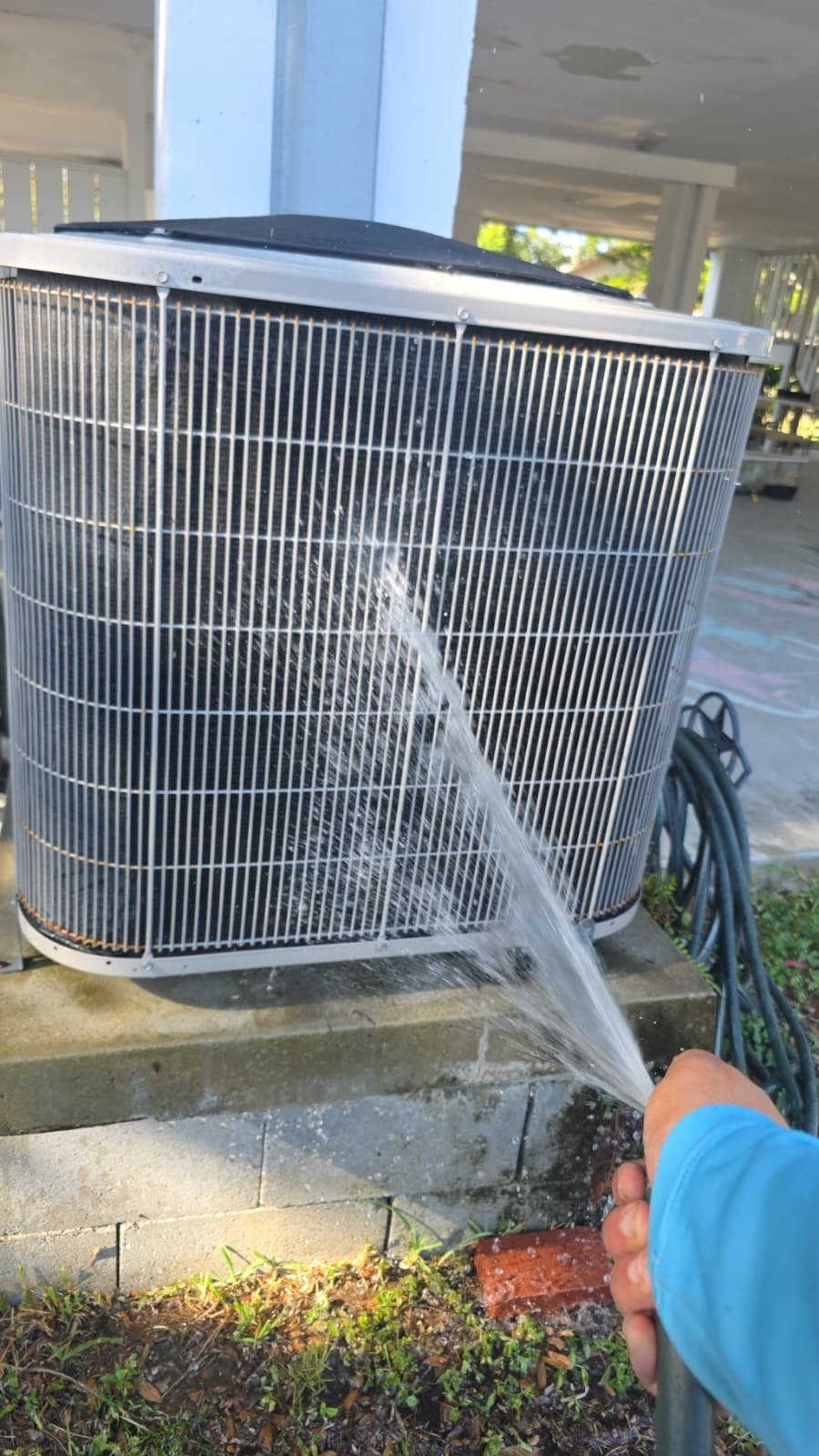 Outdoor AC unit cleaning with hose during Premium Therapy Plan in St. Petersburg, FL 33703.